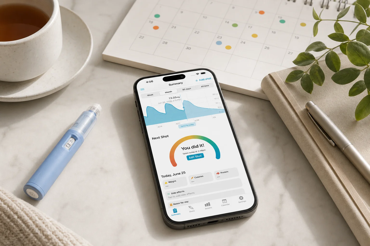 Shotsy app on a phone beside a calendar, tea, notebook, and GLP-1 injection pen