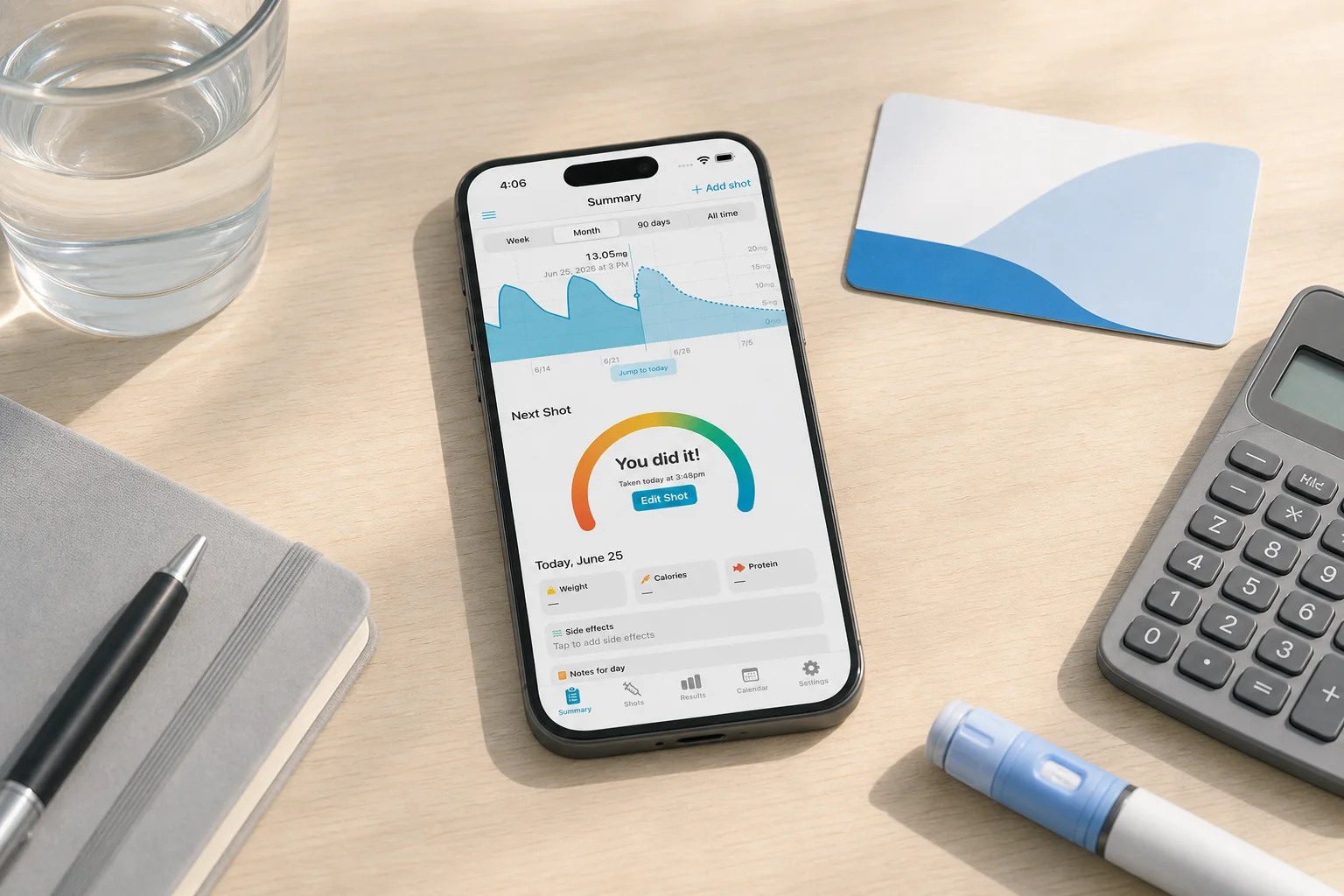 Shotsy app on a phone beside an insurance card, calculator, notebook, and GLP-1 injection pen
