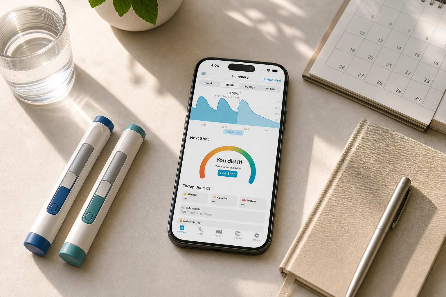 Shotsy app on a phone beside two GLP-1 injection pens, calendar, notebook, and water