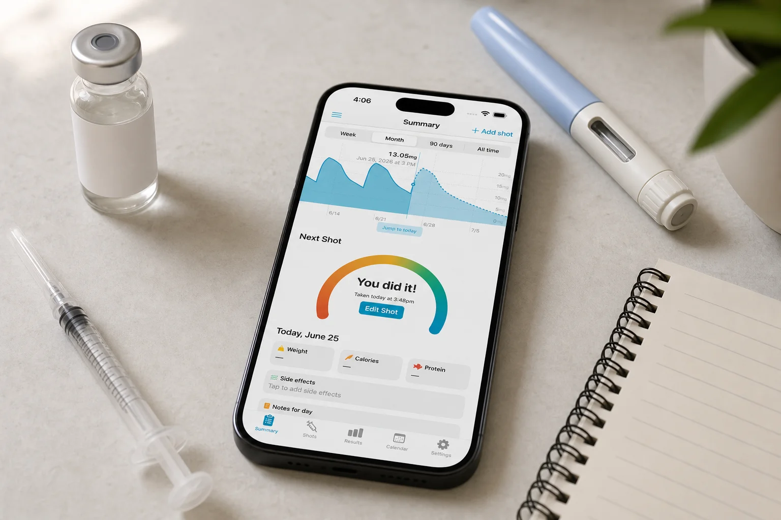 Shotsy app on a phone beside an unlabeled vial, syringe, notebook, and GLP-1 injection pen
