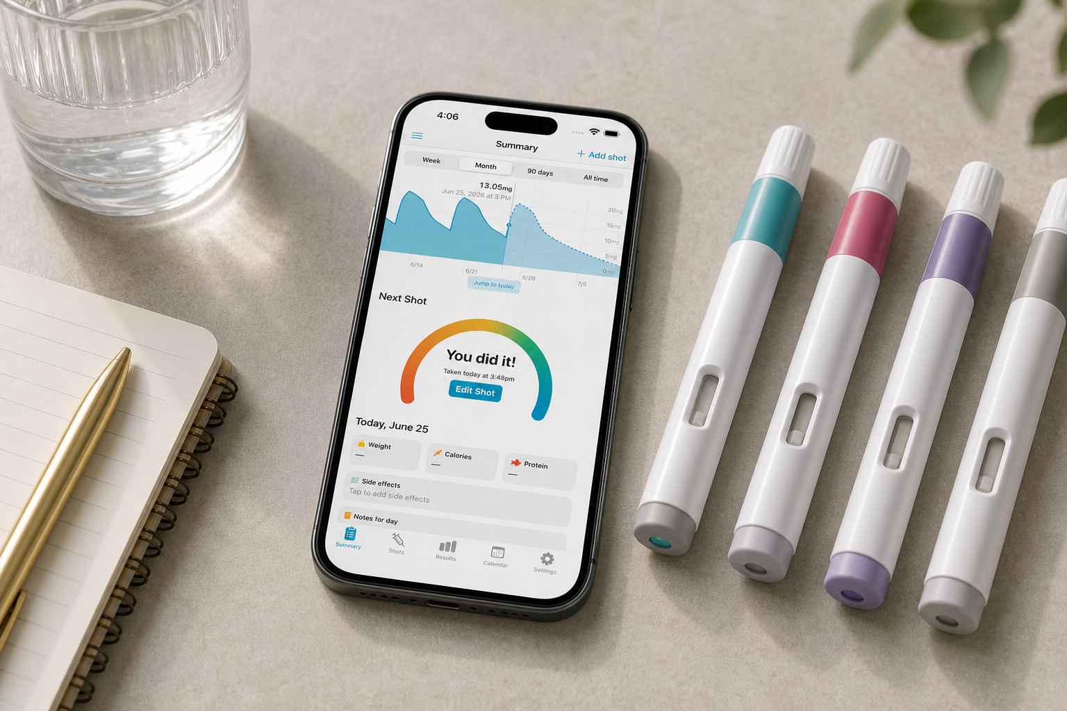 Shotsy app on a phone beside four unlabeled GLP-1 injection pens, notebook, and water