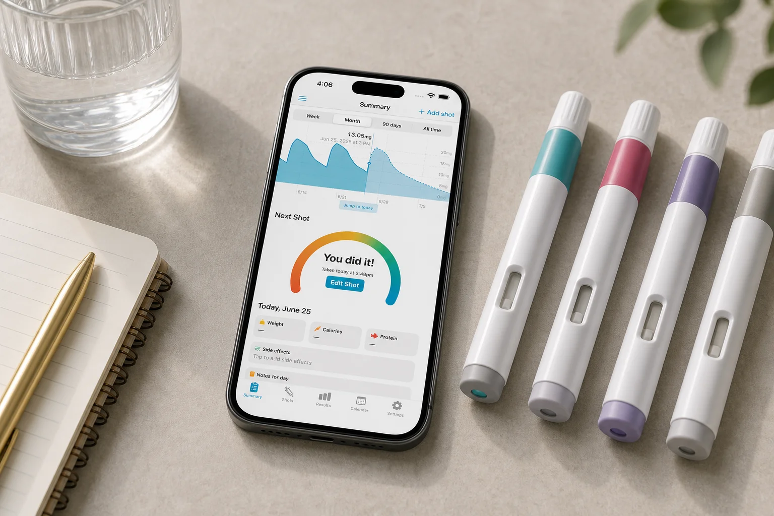 Shotsy app on a phone beside four unlabeled GLP-1 injection pens, notebook, and water