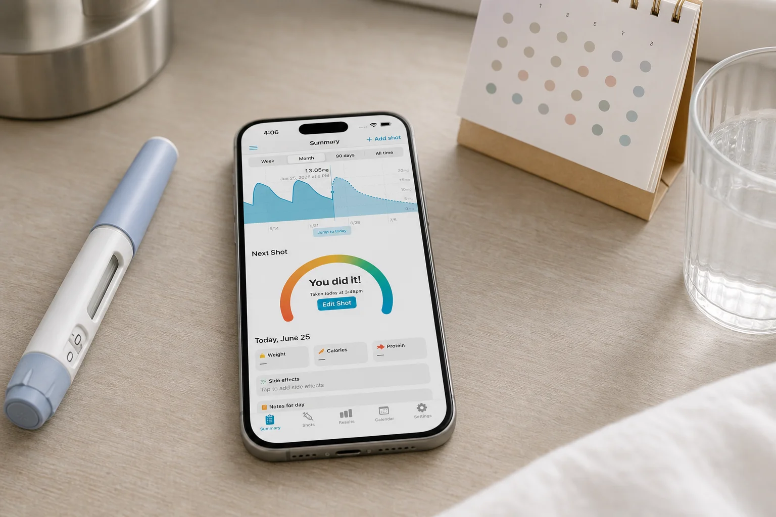 Shotsy app on a phone beside a GLP-1 injection pen, calendar, and water glass